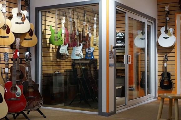 Cabina insonorizada con guitarras colgadas en la pared.