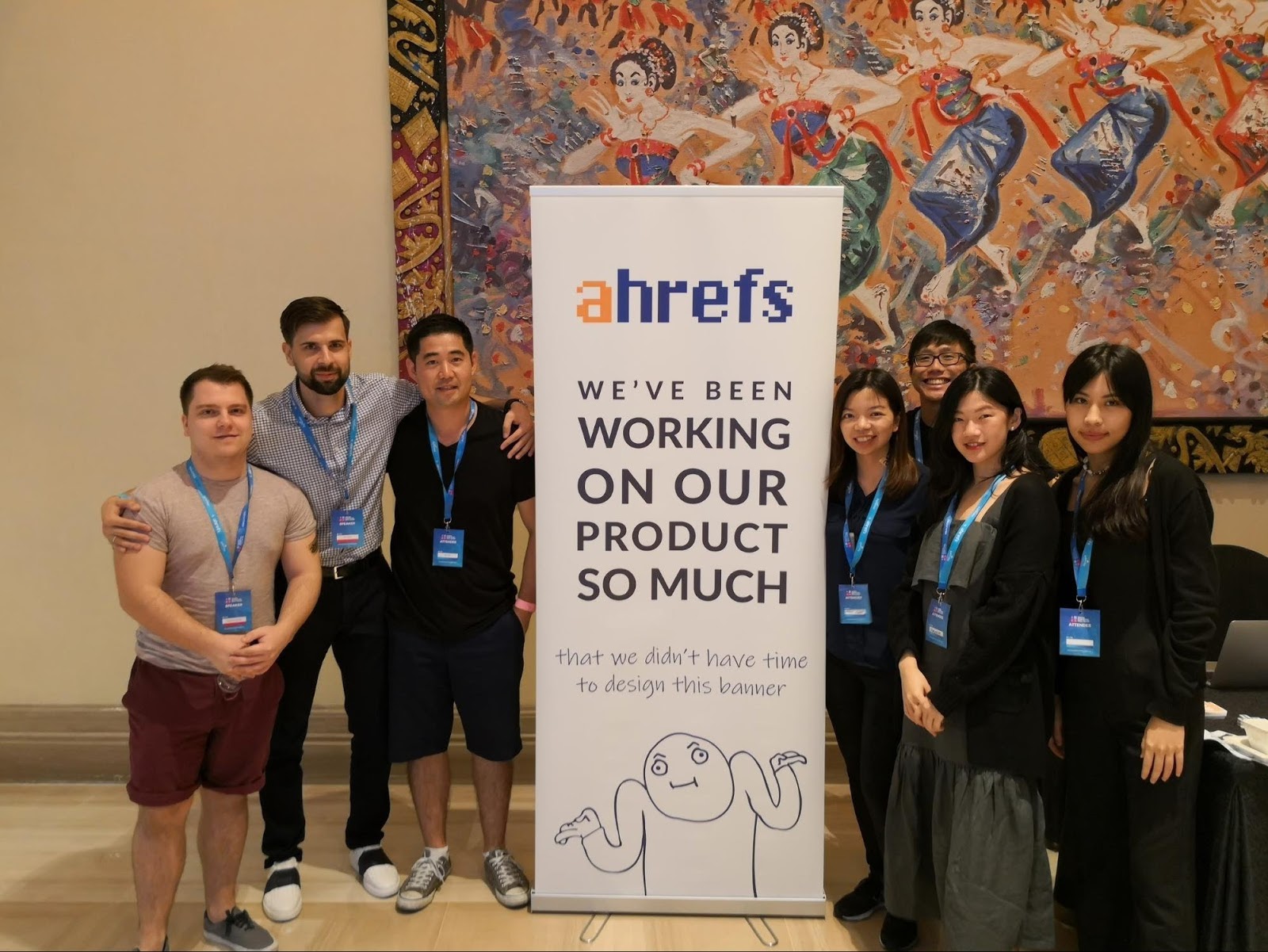 Photo of Ahrefs team and banner with rough sketches on it with words "We've been working on our product so much that we didn't have time to design this banner"