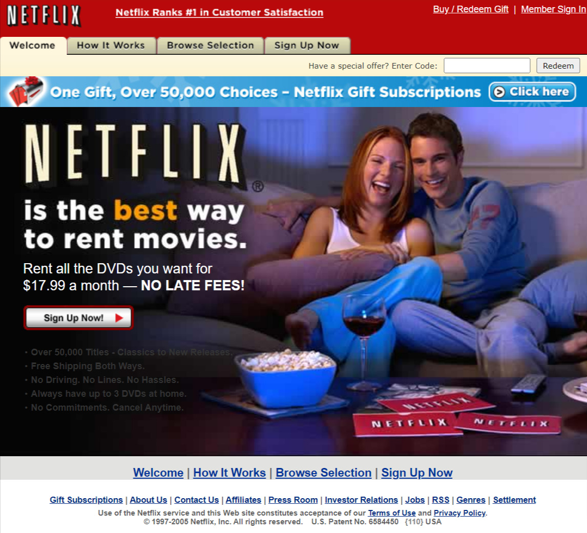 Netflix's homepage. CTA on left; on right, a couple on the sofa laughing and having popcorn and wine