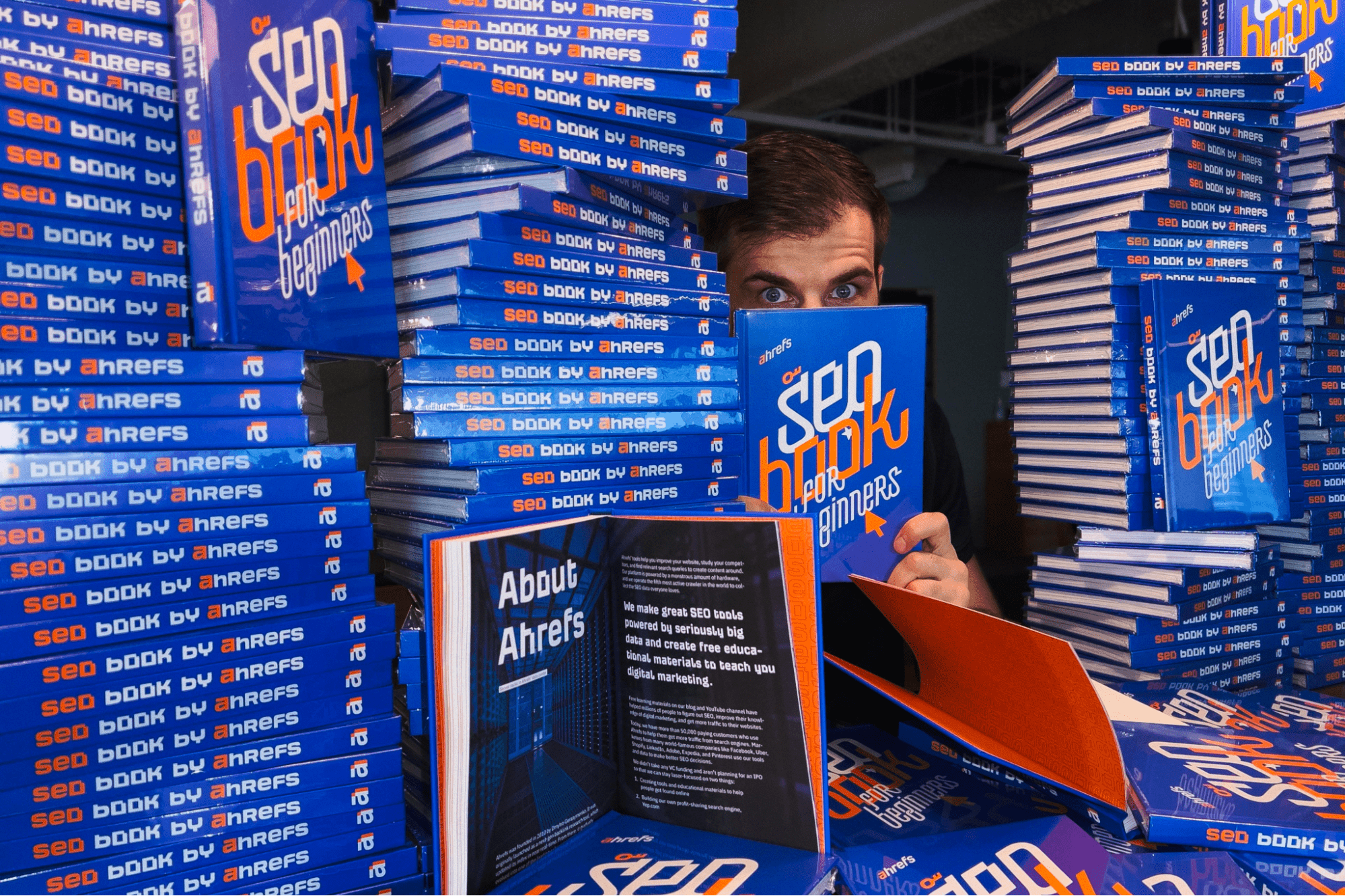 Ahrefs CMO Tim Soulo amid stacks of the company's book, "SEO Book for Beginners"
